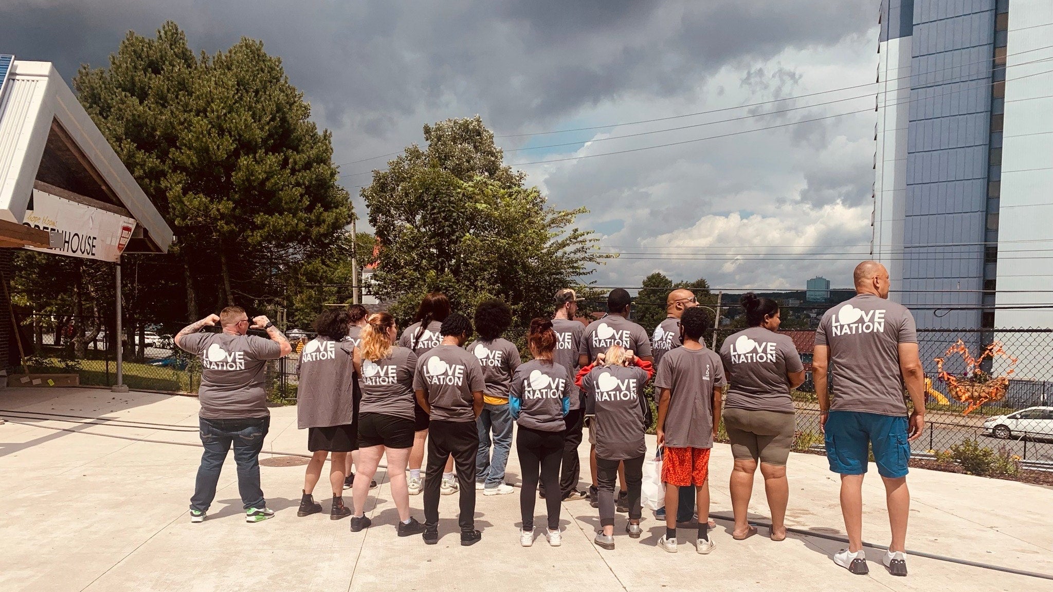 Group of people wearing matching gray t-shirts with 'Love Nation' text on a sidewalk.